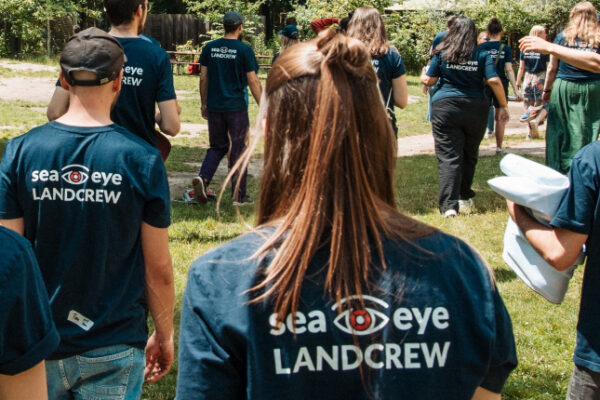 Gruppe von Sea-Eye-Landcrew-Mitgliedern in dunkelblauen Shirts läuft durch einen Park