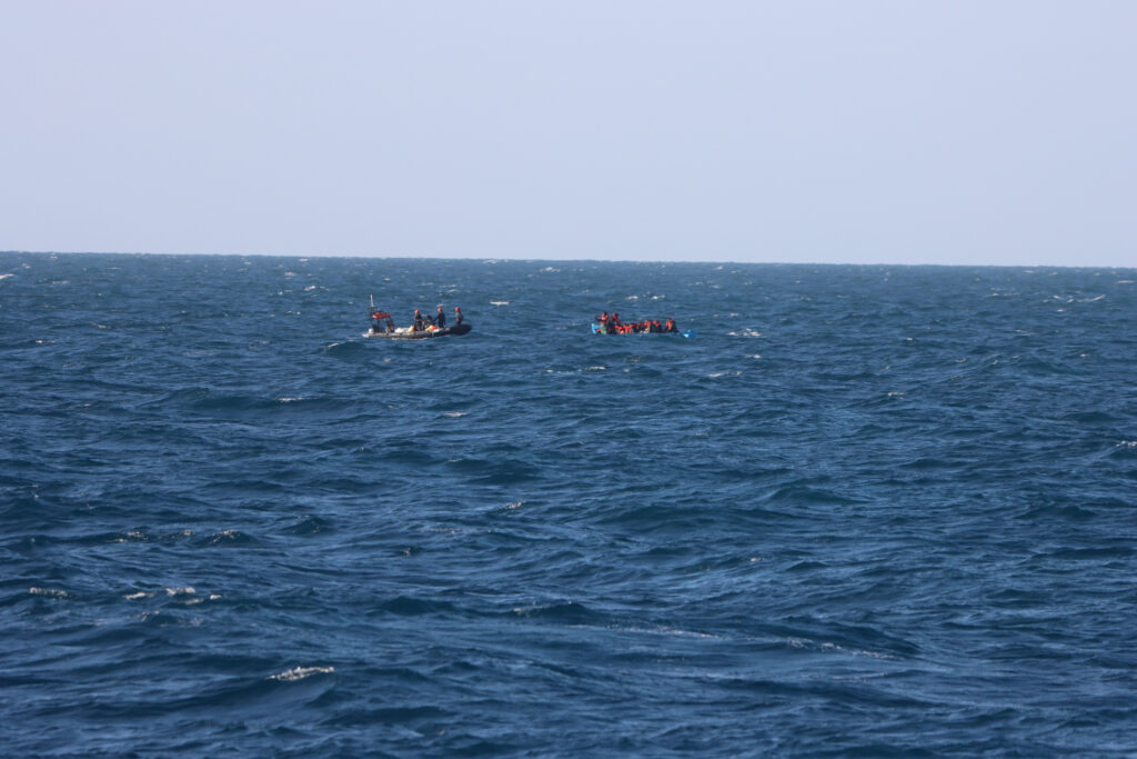 Sea-Eye-RHIB nähert sich einem überfüllten Schlauchboot mit Menschen in Rettungswesten auf dem Mittelmeer