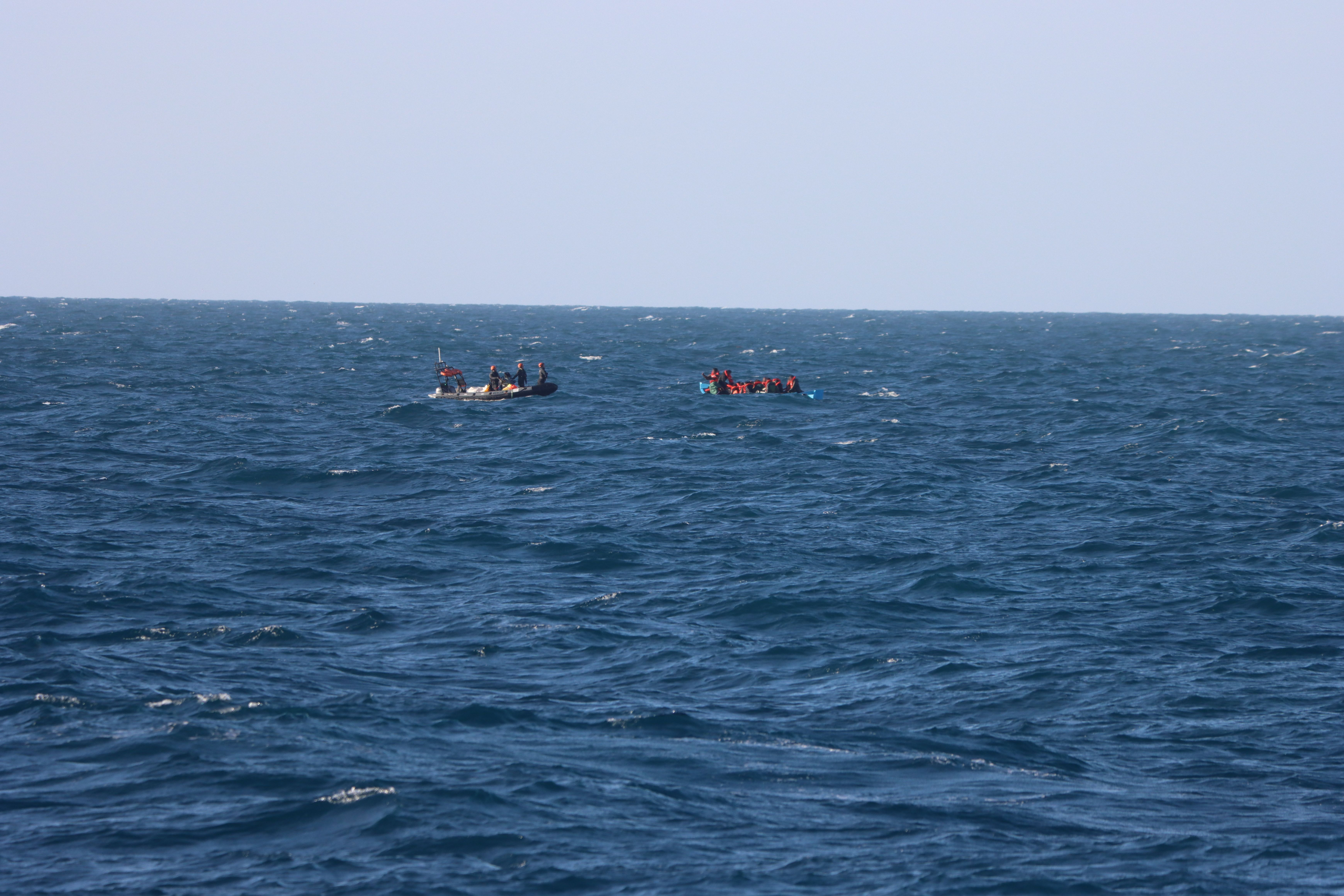 Sea-Eye-RHIB nähert sich einem überfüllten Schlauchboot mit Menschen in Rettungswesten auf dem Mittelmeer