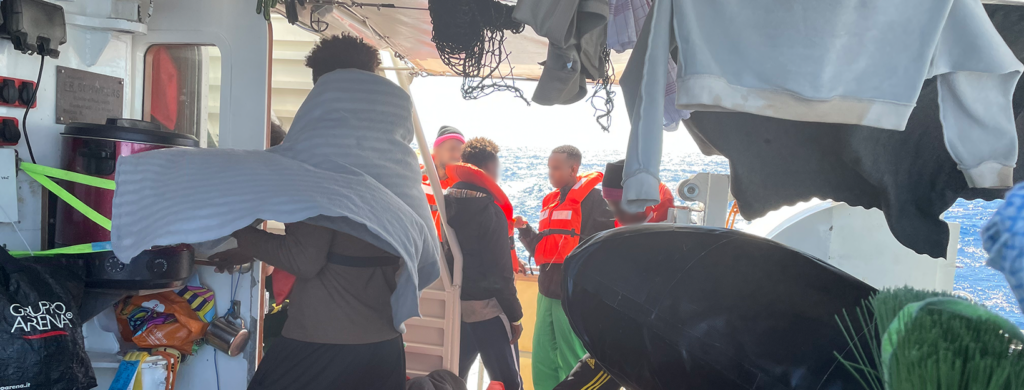 Gerettete Menschen in Rettungswesten stehen dicht gedrängt an Deck der SEA-EYE 5 auf dem Mittelmeer