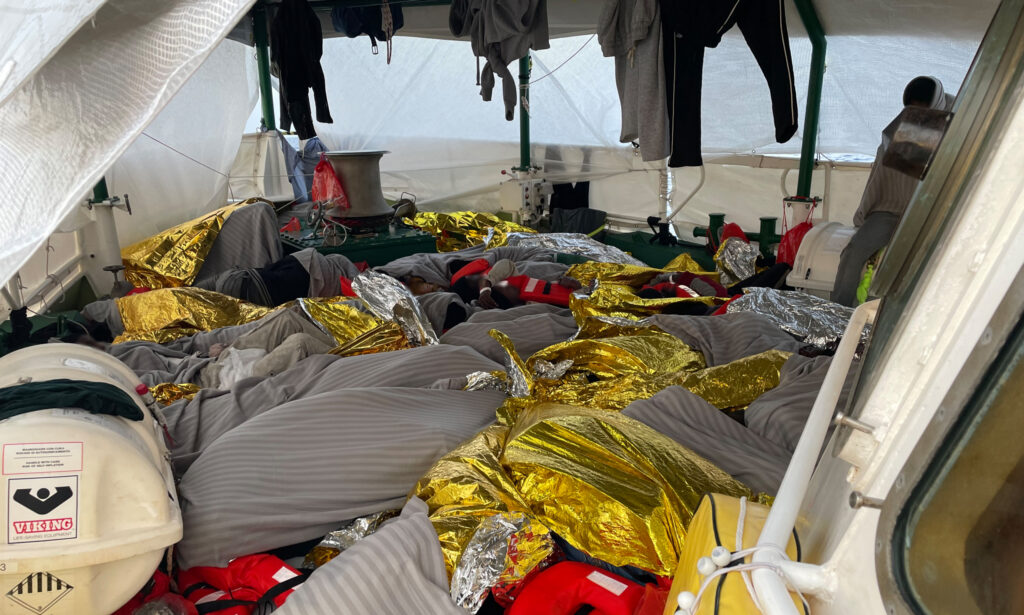 Gerettete Menschen ruhen unter Rettungsdecken auf dem Deck der SEA-EYE 5