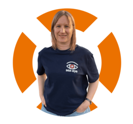 Porträt von Claudia, HR- Head bei Sea-Eye, in Sea-Eye-Shirt vor orangefarbenem Hintergrund