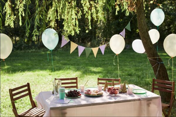 Ein gedeckter Tisch im Garten mit Luftballons und Girlande.